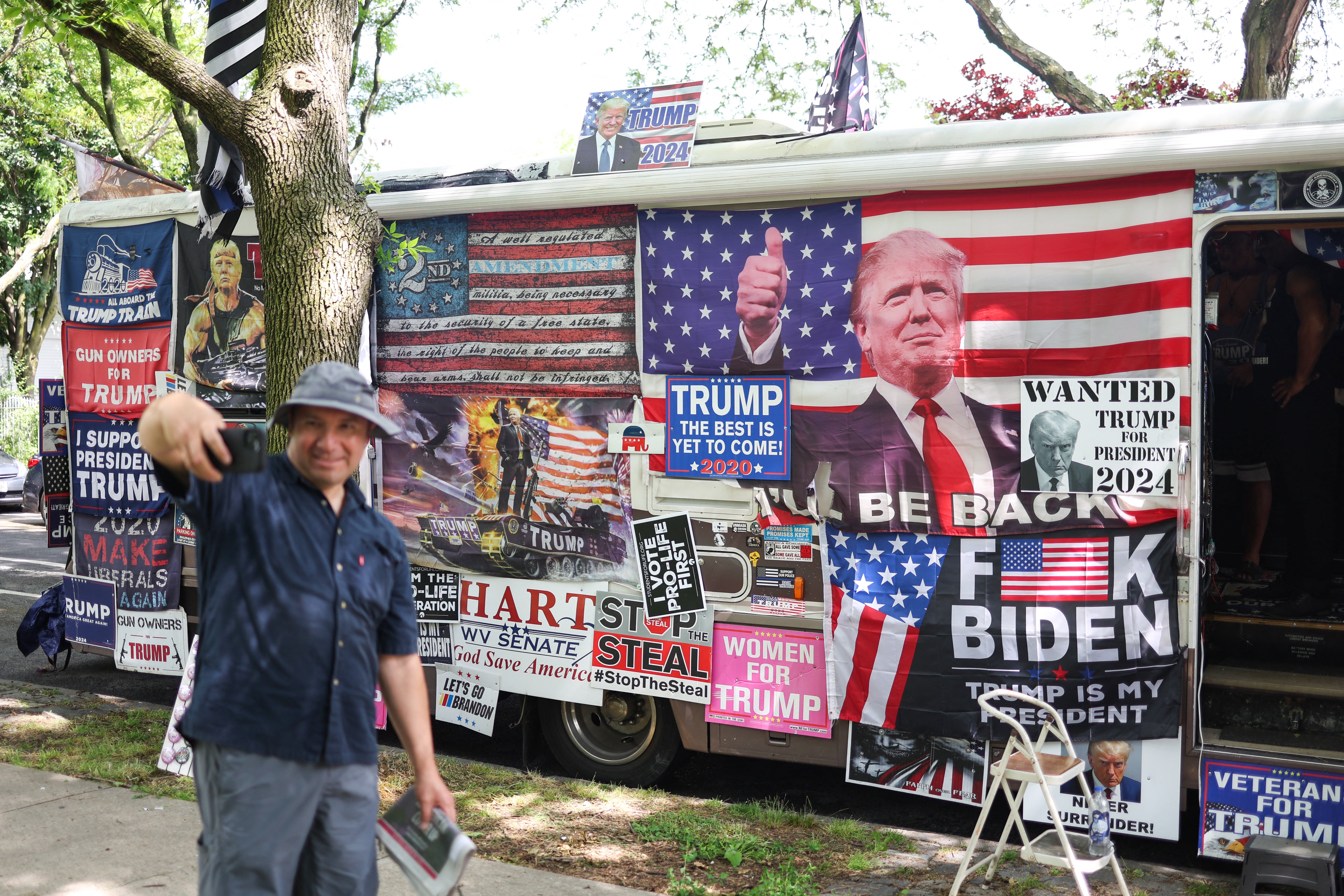 A supporter of former US President Donald Trump takes a picture outside a merchandise stand in an RV ahead of a campaign rally at Crotona Park in the South Bronx, New York City