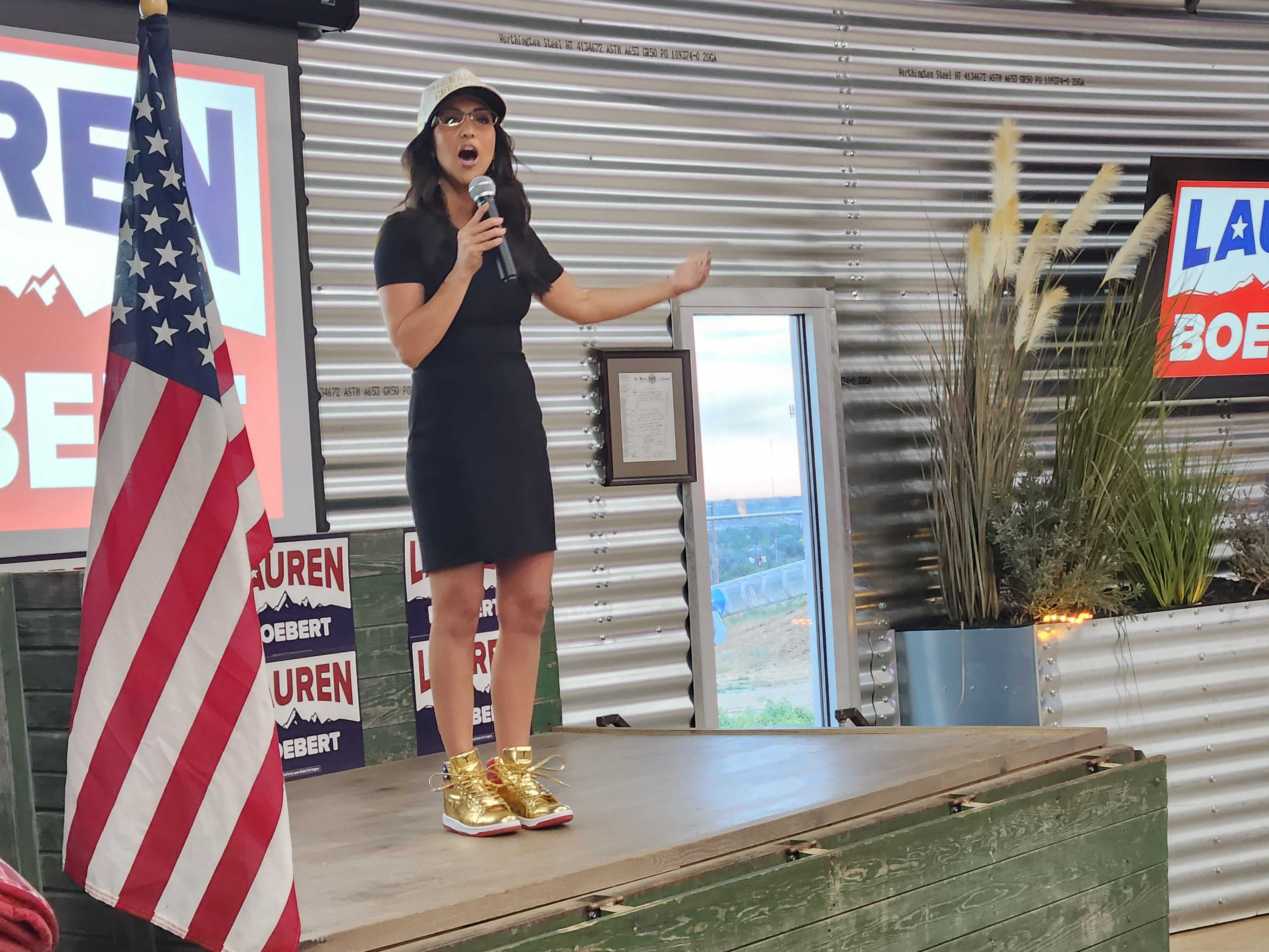 Lauren Boebert, wearing a pair of gold Trump sneakers, speaks to supporters after winning her primary race