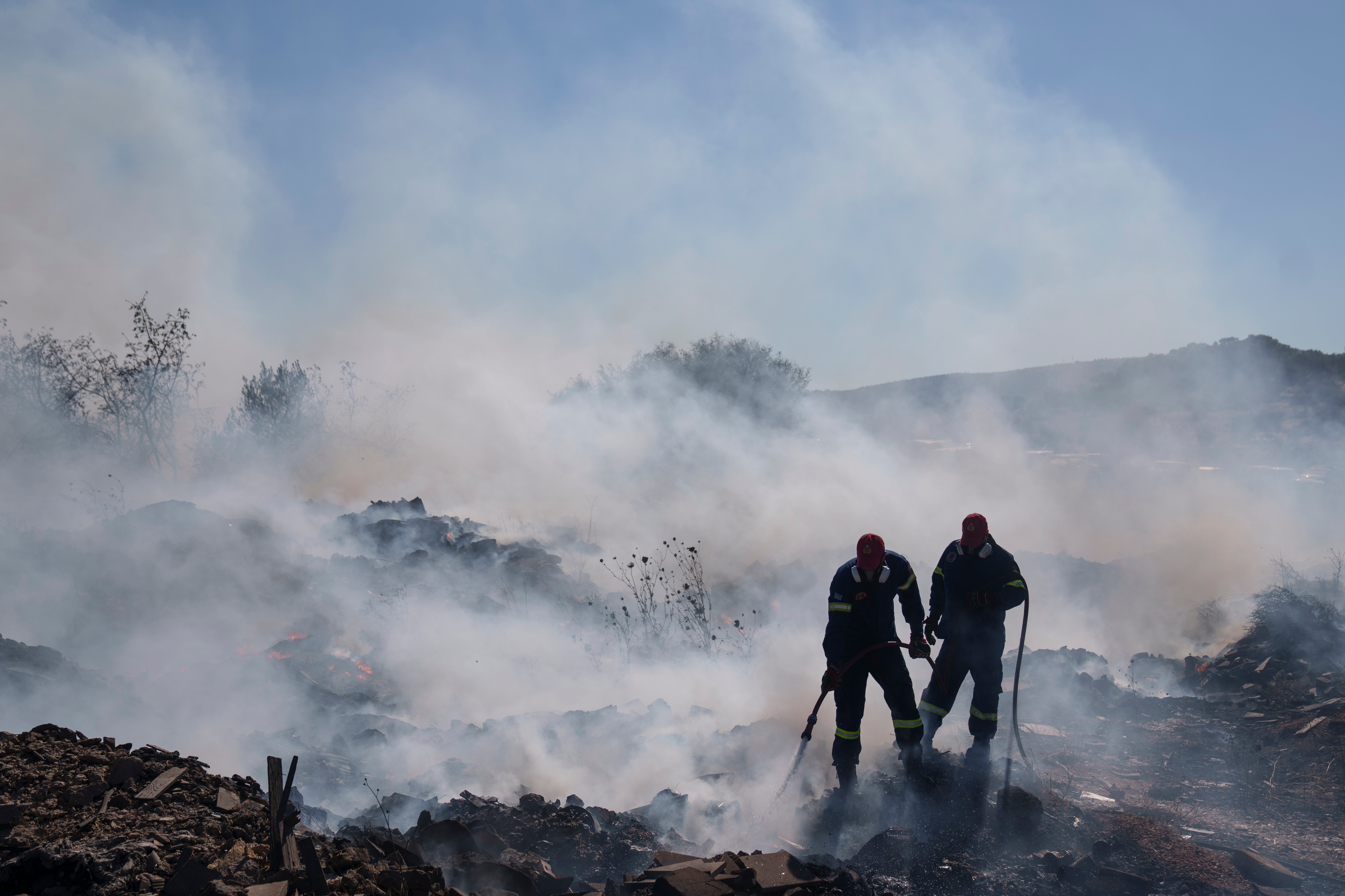 Firefighters try to extinguish the fire burning in Koropi suburb in the eastern part of Athens on Wednesday