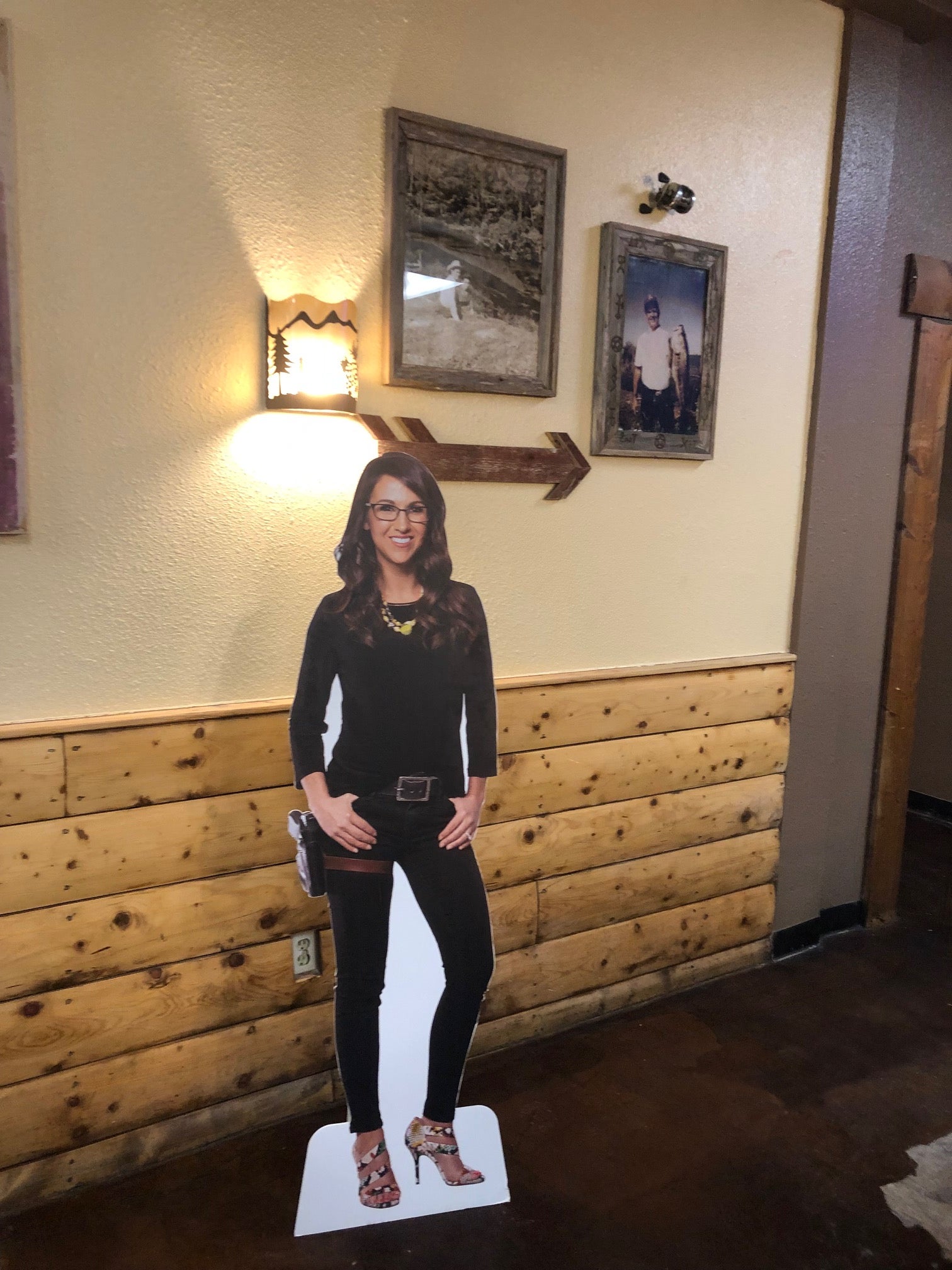 A cardboard cutout of a holstered Lauren Boebert helped point the way to the bathroom at her restaurant before it closed; tourists would take photos of themselves with the cutout and a cardboard cutout of Trump