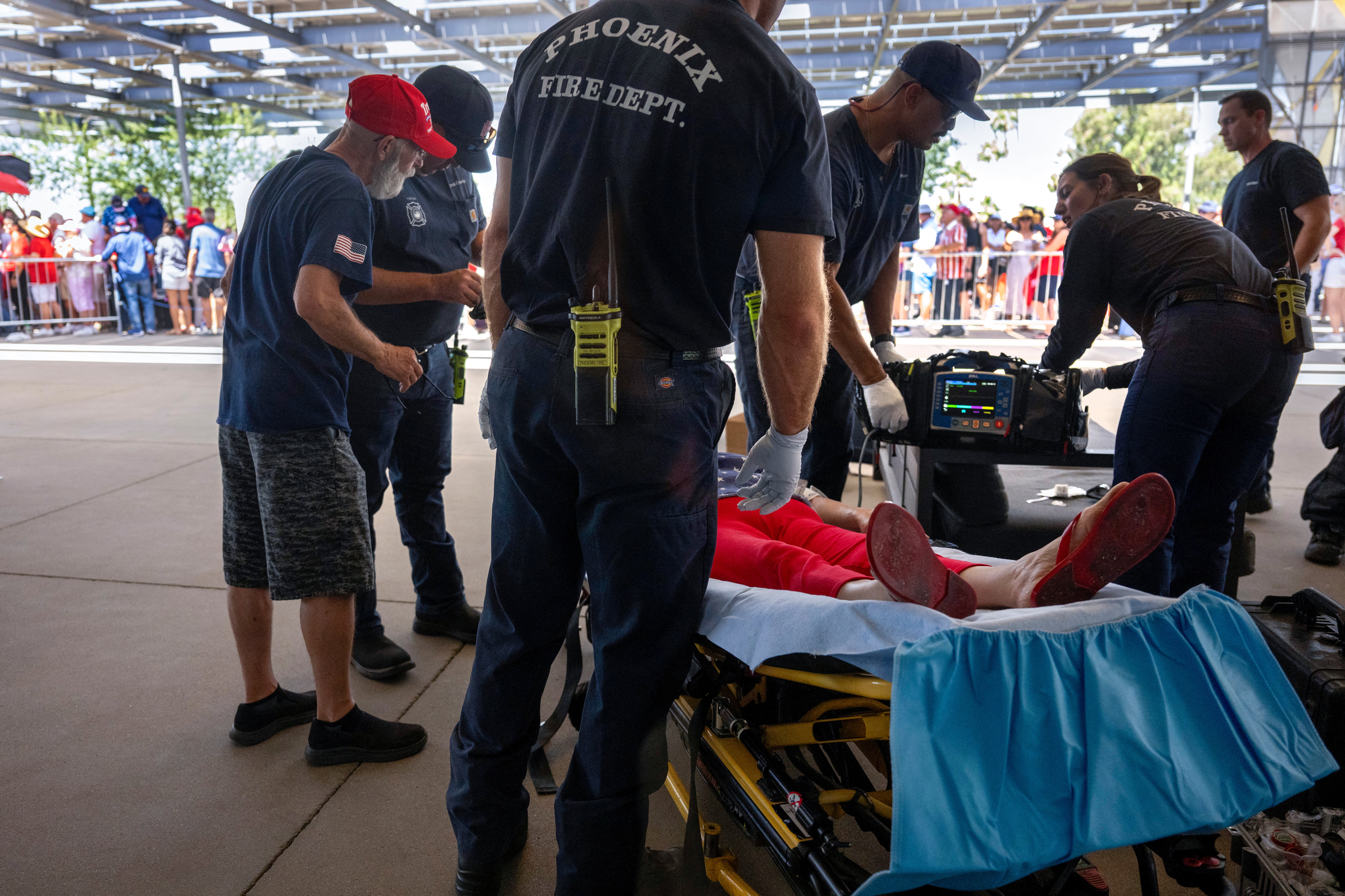 As temperatures reach 108 degrees Farenheit (42C), a woman is tended to for heat exhaustion as supporters line up before former US President and 2024 Republican presidential candidate Donald Trump participates in a town hall event