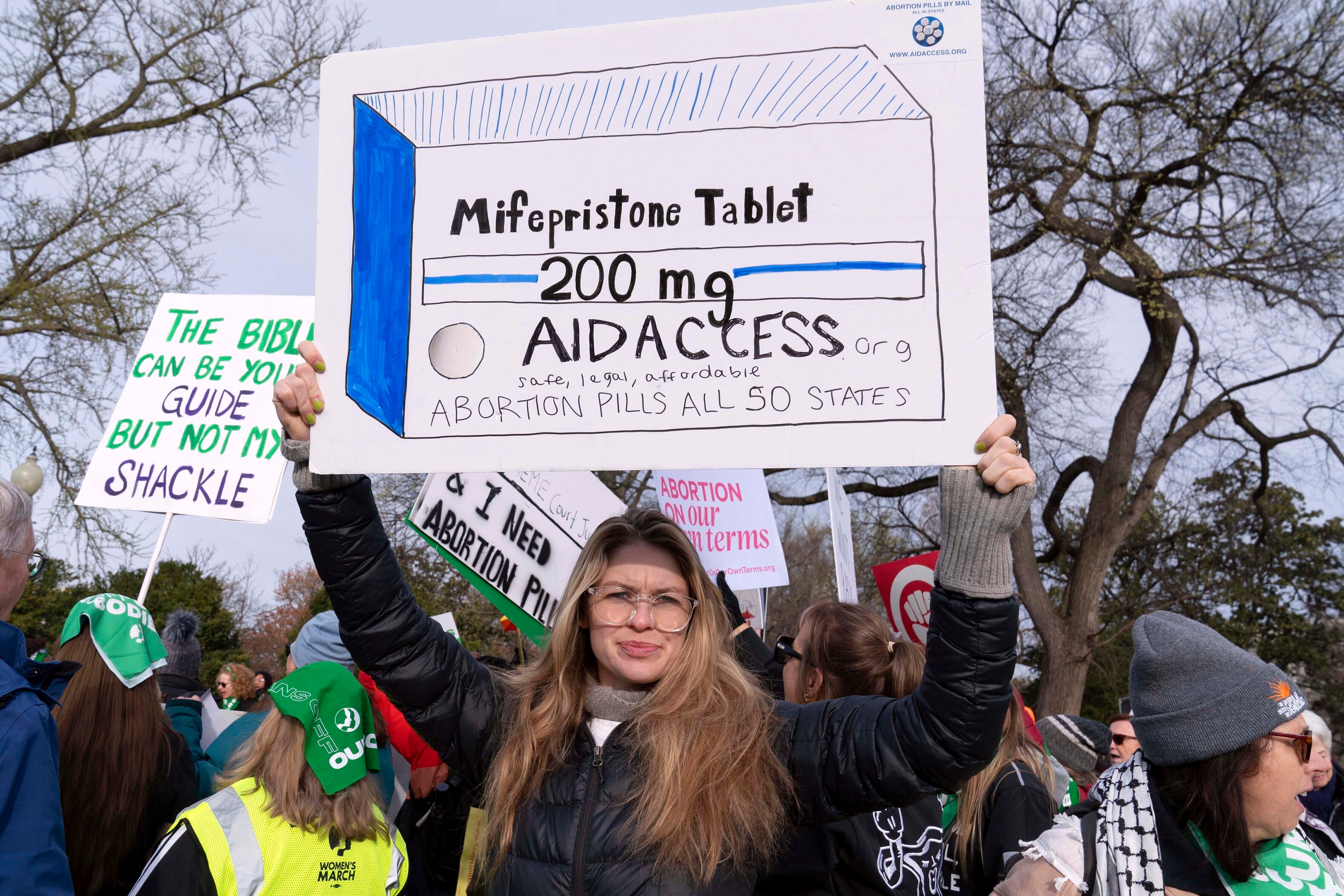 Abortion-rights activists holds a signs as they protest outside of the Supreme Court during a rally, March 26, 2024