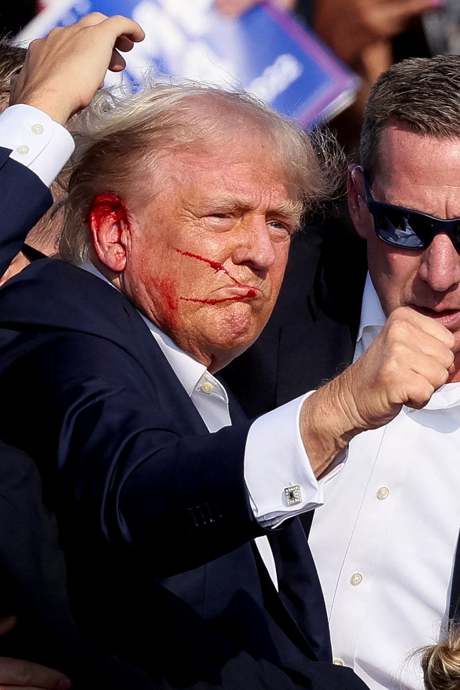 Donald Trump raises his fist to a campaign rally crowd after he appeared to be struck by gunfire