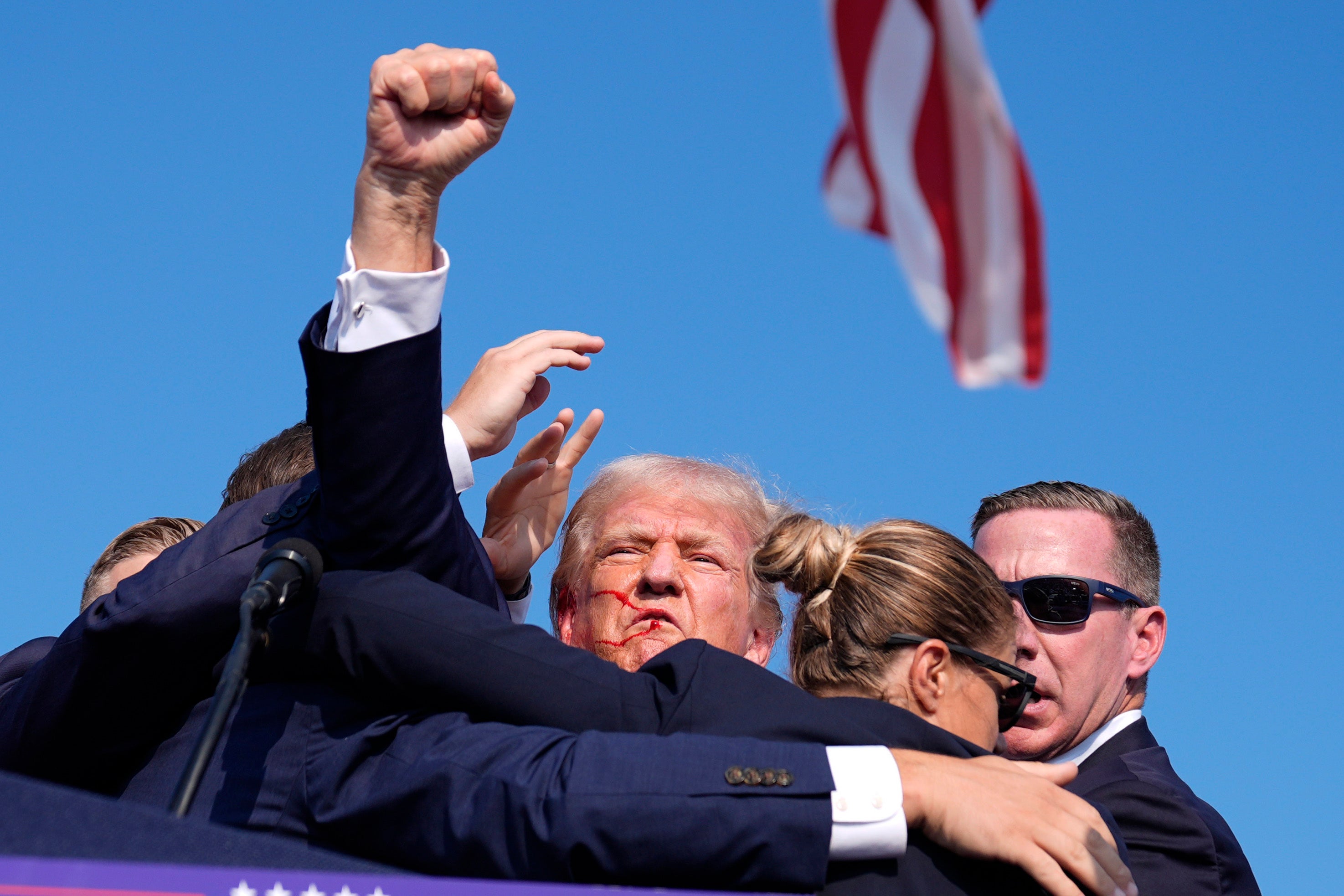 Trump punched the air in defiance as he returned to his feet and was hustled off the stage, moments after shots rang out at his Pennsylvania rally