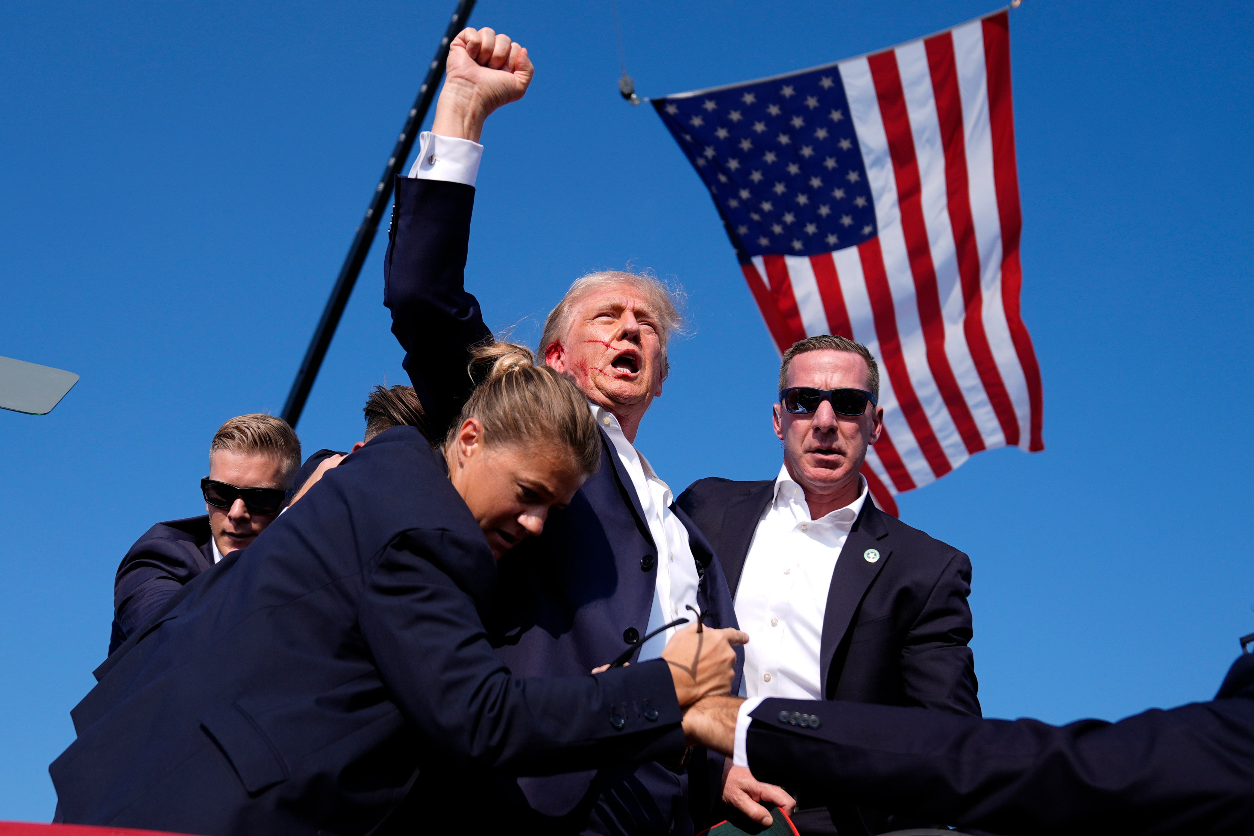 Republican presidential candidate former President Donald Trump is surrounded by U.S. Secret Service agents after an assassination attempt at a campaign rally in Butler, Pa., Saturday, July 13, 2024