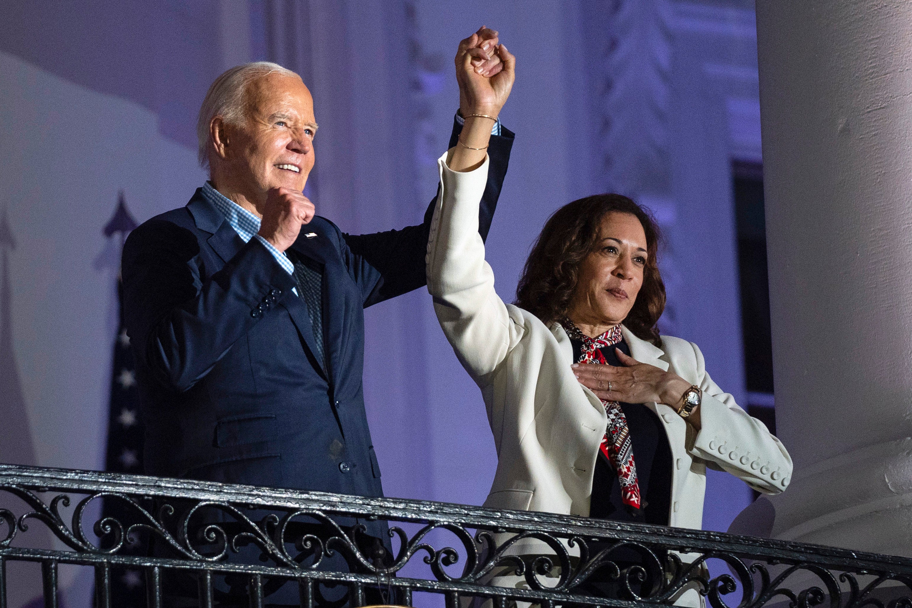 Biden raises the hand of Vice President Kamala Harris after viewing the Independence Day fireworks display over the National Mall from the balcony of the White House. The outgoing president has backed Harris as the Democratic nominee.