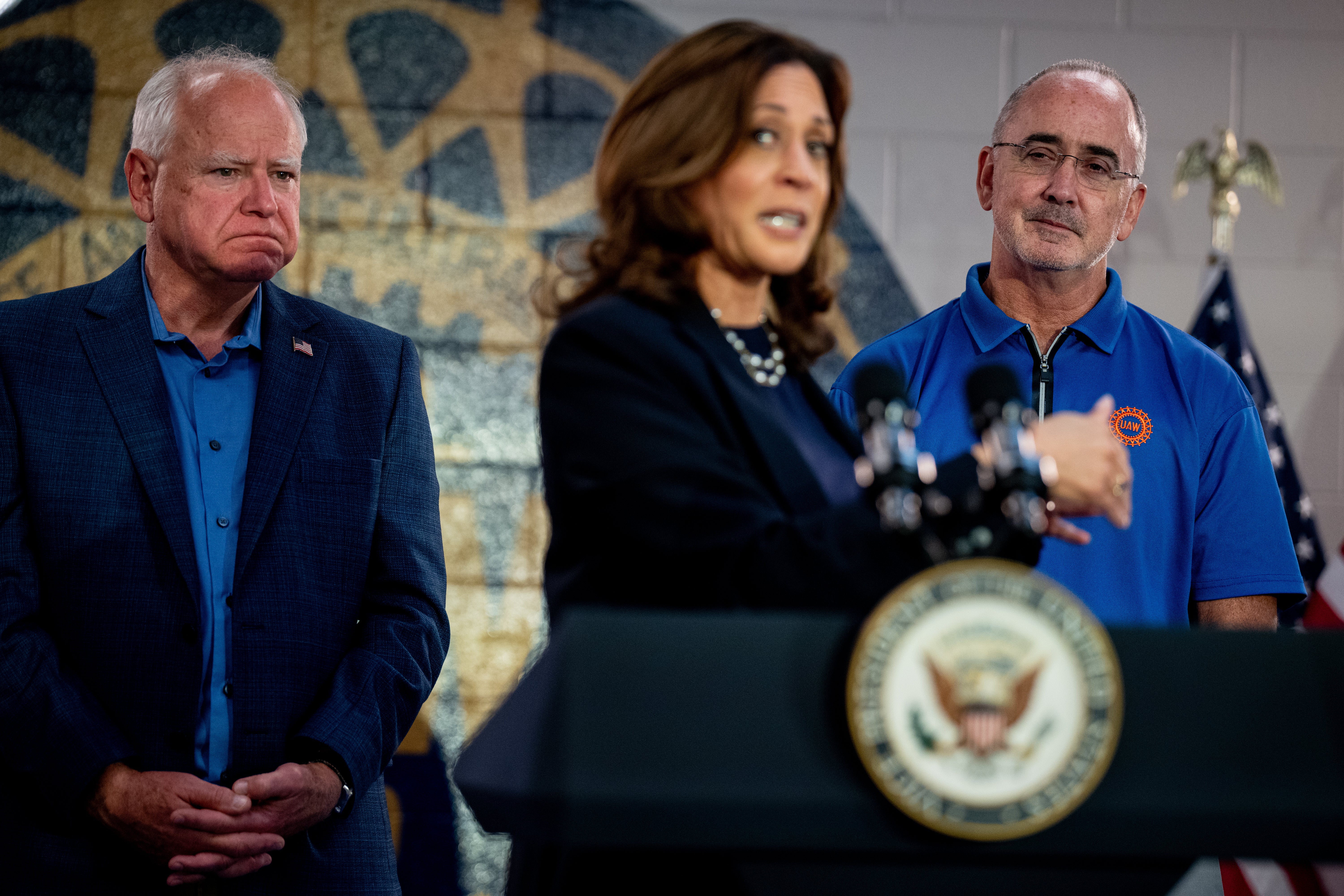 Kamala Harris speaks next to United Automobile Workers president Shawn Fain, right, and her running mate Tim Walz, left, at a United Auto Workers Local 900 outpost in Michigan on August 8.