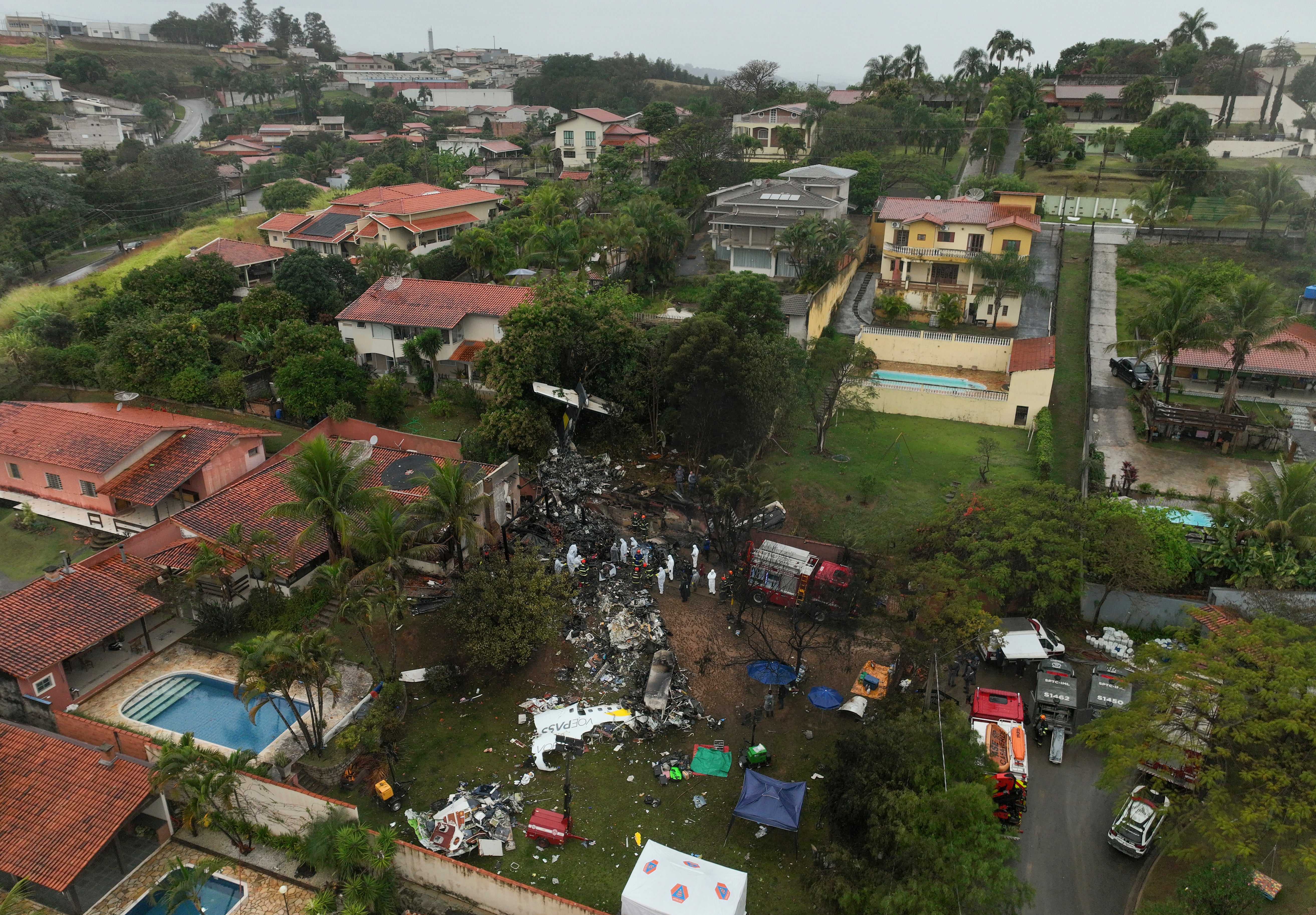 Firefighters and rescue teams work at the site in a residential area where an airplane with 62 people on board crashed in Vinhedo