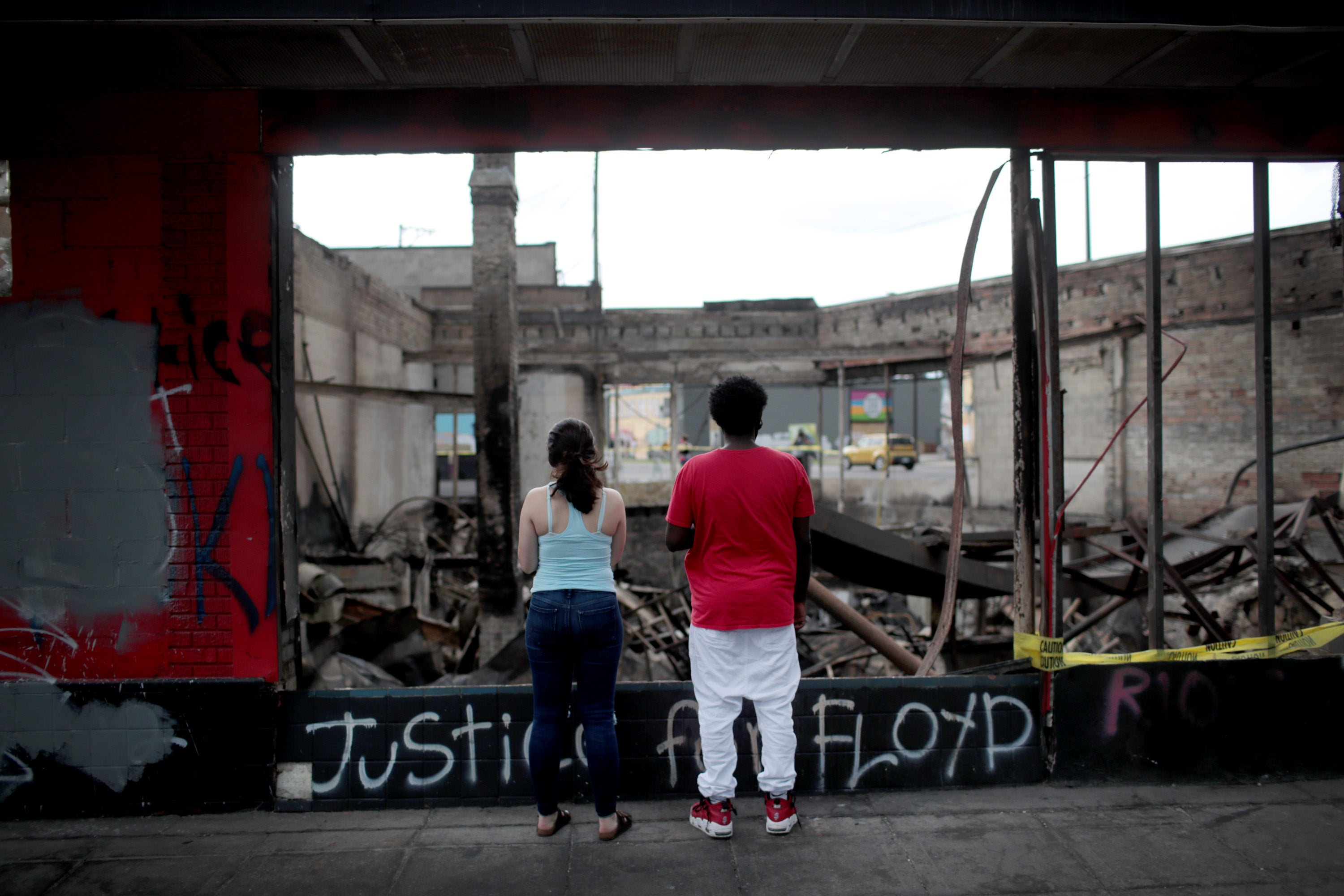 People look at the charred wreckage of a building destroyed during last week's rioting which was sparked by the death of George Floyd on June 2, 2020 in Minneapolis, Minnesota