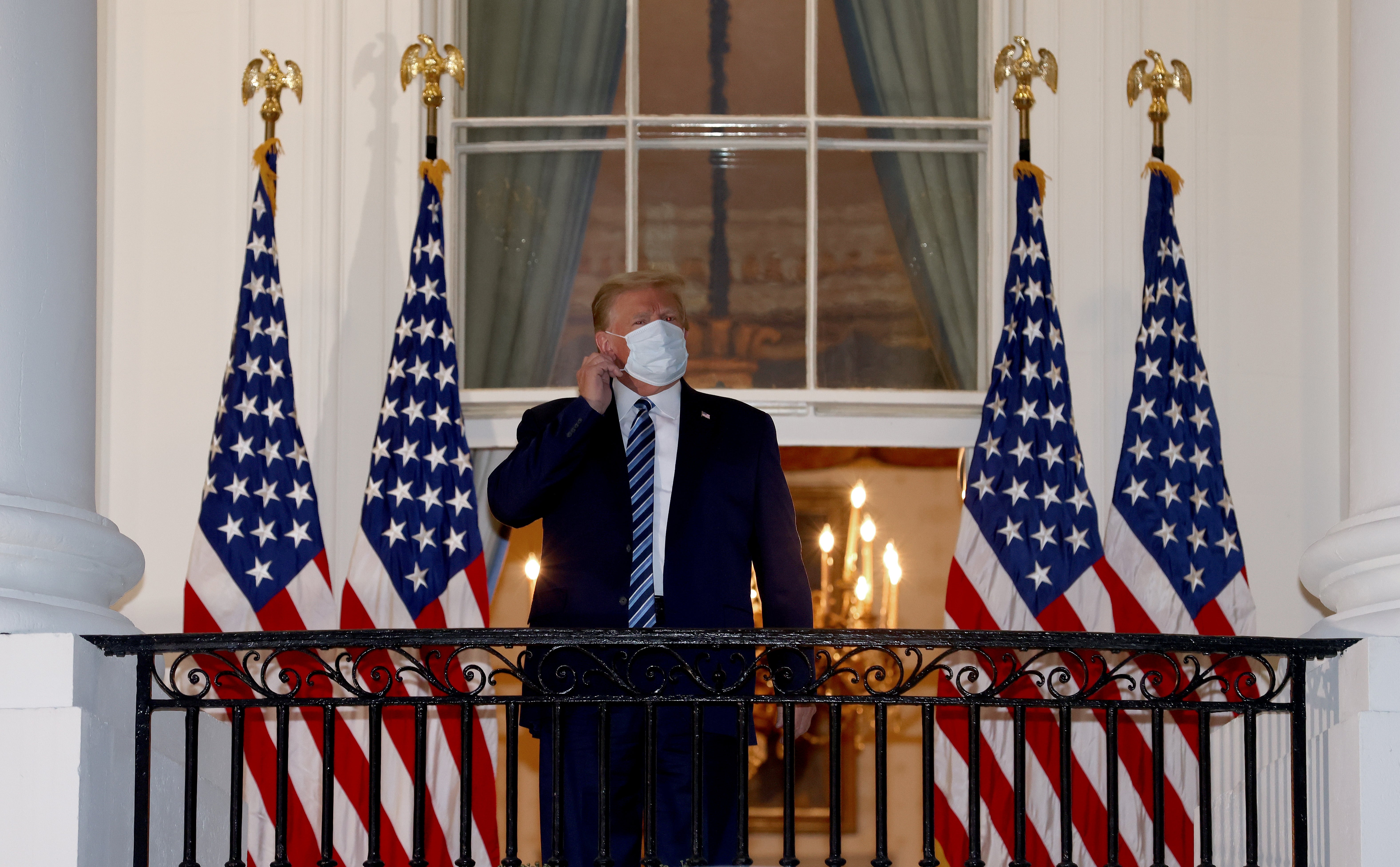 U.S. President Donald Trump reaches to remove his mask upon return to the White House from Walter Reed National Military Medical Center on October 05, 2020 in Washington, DC