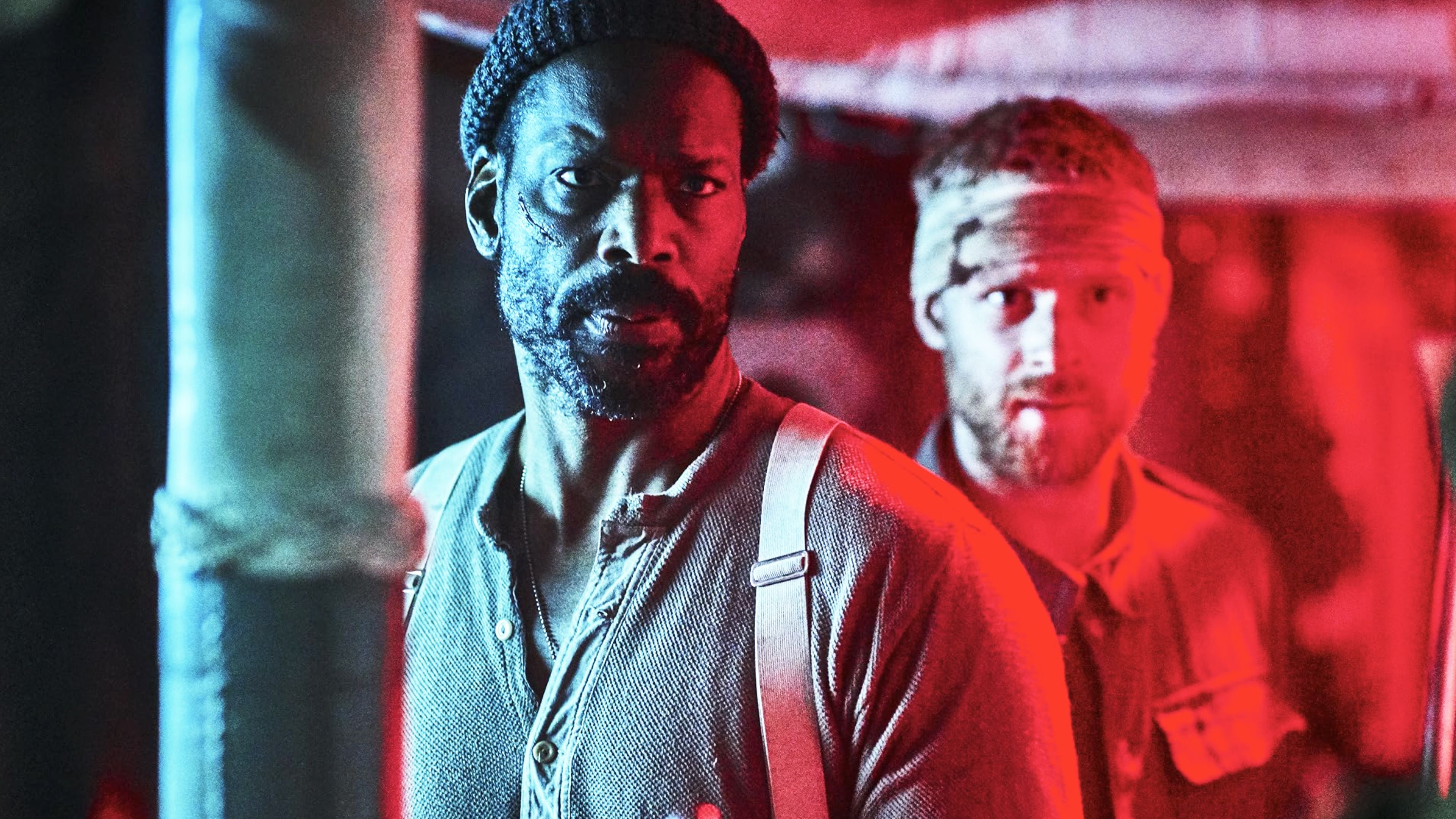 Two Allied survivors stand in red and blue light aboard a German vessel in the World War II horror movie Blood Vessel.